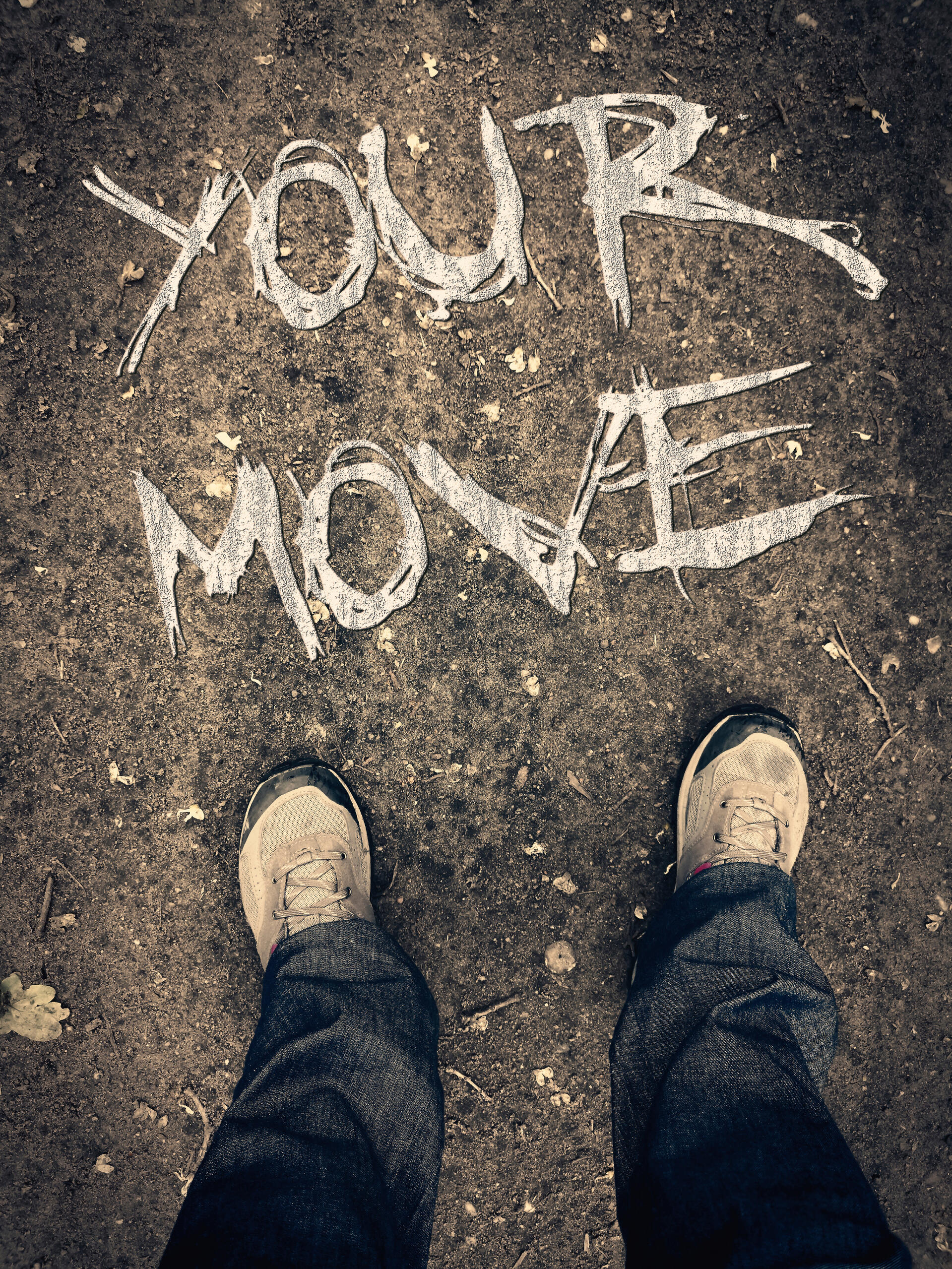 Your Move Image with "your move" written on the ground from the perspective of a woman looking down at her hiking boots and pants legs out on a dirt trail.